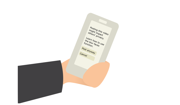 A hand is holding a phone. On its screen is a message saying Posting this video might impact others' privacy. Learn how to use the blur faces function. There are two buttons below the message, one saying Post anyway the other saying Cancel